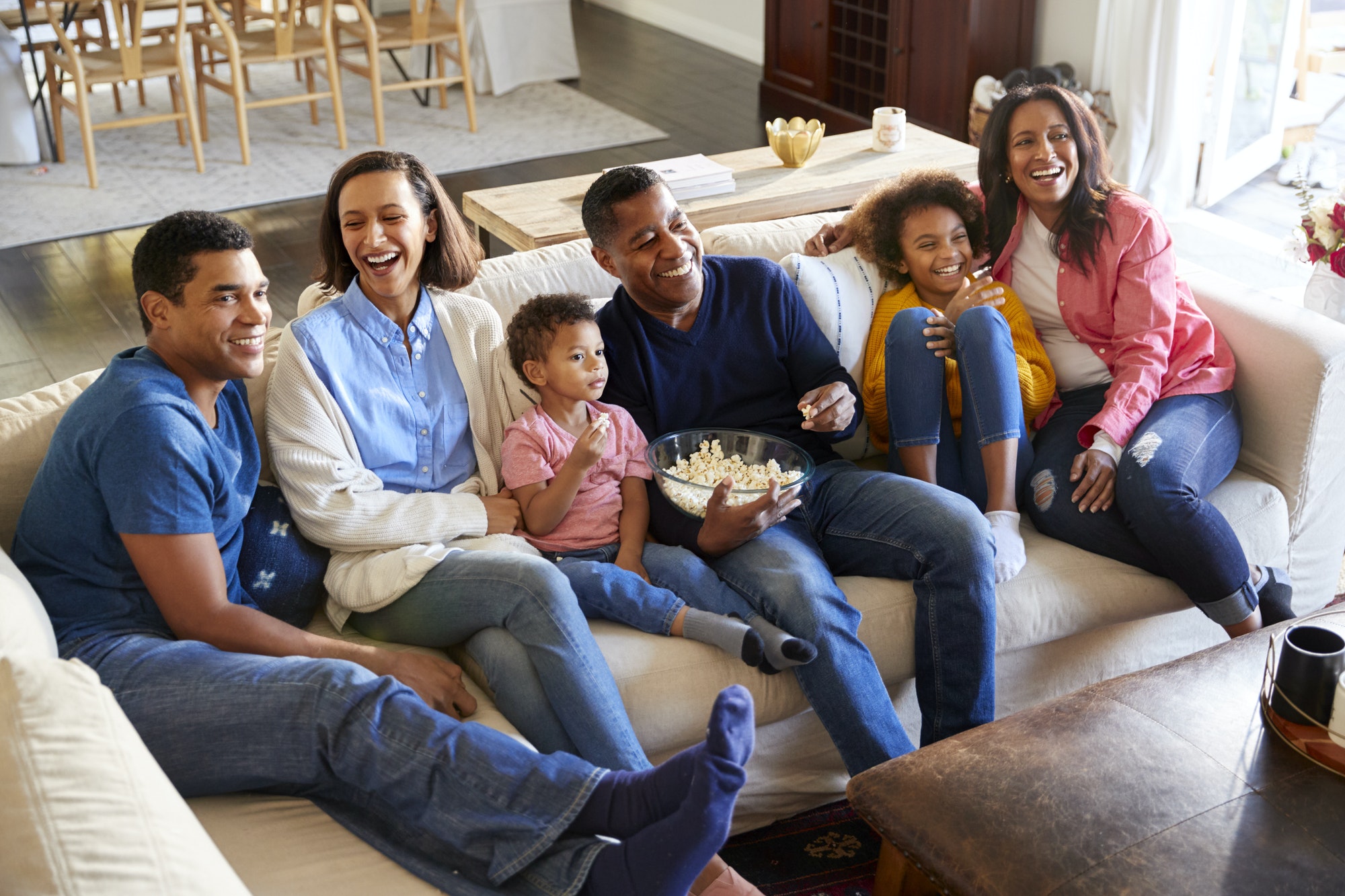 Three generation family mixed race family sitting on the sofa in living room, watching TV